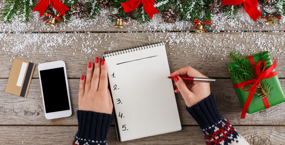 mujer escribiendo en una mesa en navidad los propósitos de año nuevo en una libreta 
