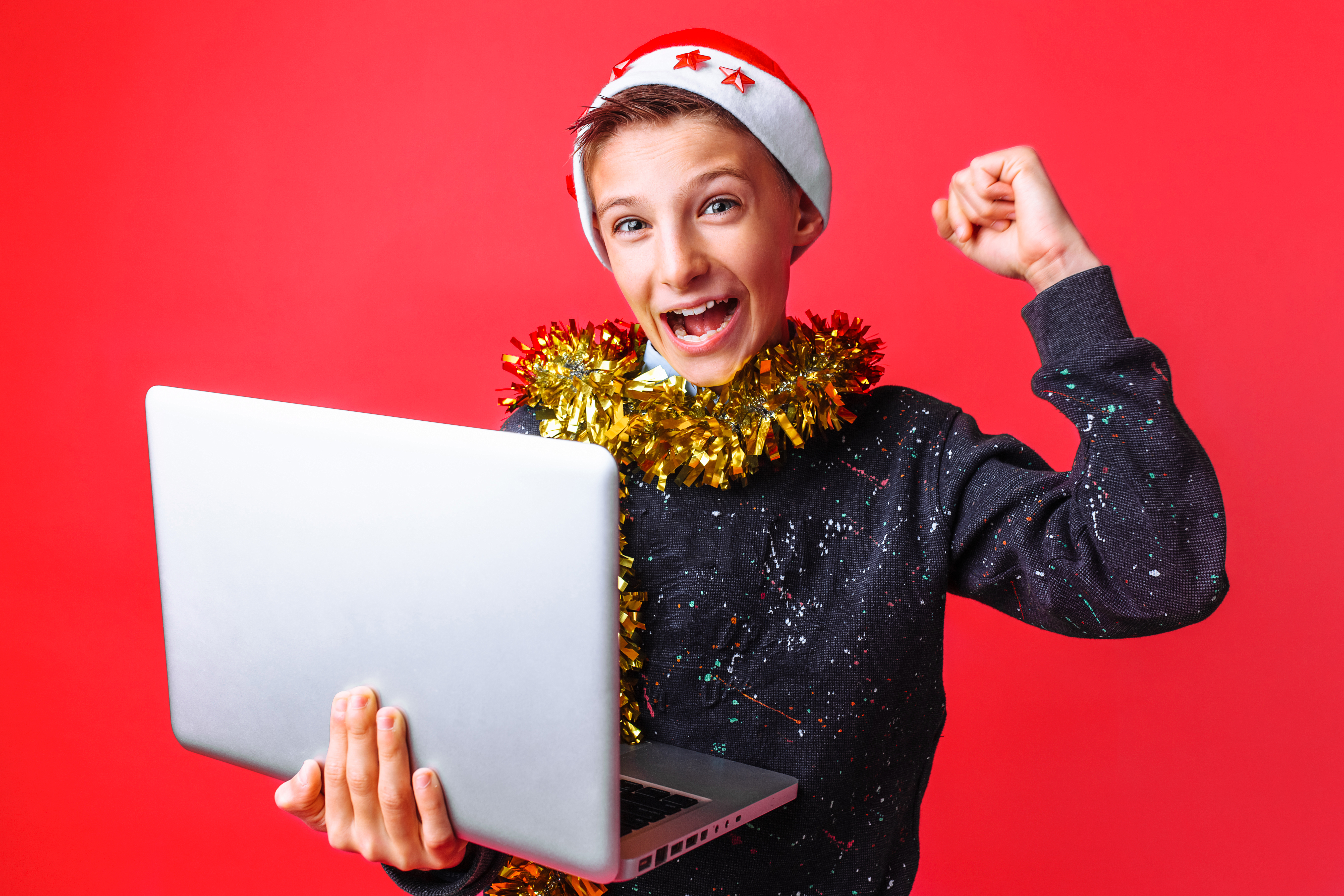 niño feliz en navidad con fondo rojo con ordenador y con gorro de papa noel