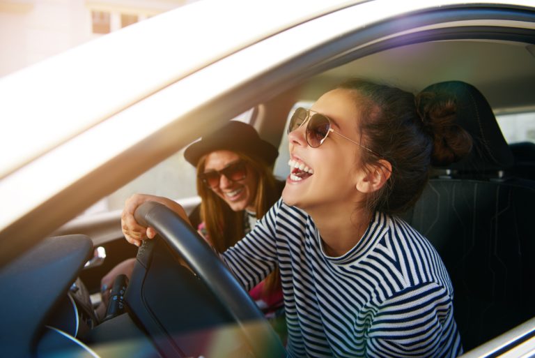dos chicas con gafas de sol en un coche felices riendose y disfrutando del viaje trayecto